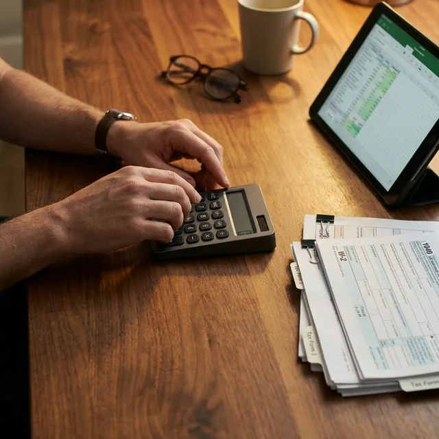 Accountant reviewing complex tax forms on an iPad with a calculator